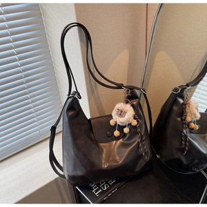 Dettaglio della borsa tote in morbida pelle nera con ciondolo alpaca bianco e chiusura magnetica