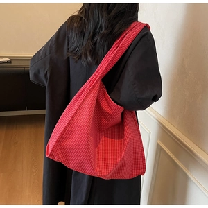 Détail de la texture du sac cabas à carreaux rouges et du tissu souple sur l'épaule