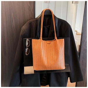 Detail of the brown woven tote bag showing the fine PU leather texture and woven pattern