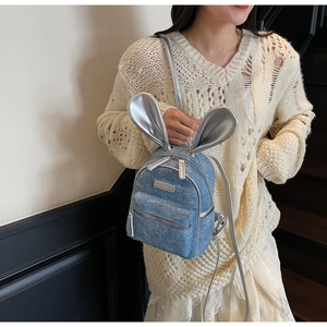 Close-up of mini denim backpack featuring silver rabbit ears and glitter finish details