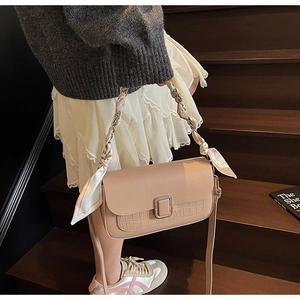 Detail of beige leather crossbody bag with crocodile texture and silk scarf strap
