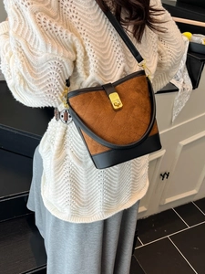 Sac seau matelassé vintage en daim marron et cuir noir porté par un mannequin femme