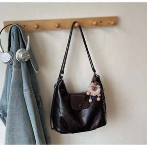Dettaglio della borsa tote in pelle marrone scuro con ciondolo a leone in peluche e finitura