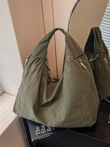 Olive green nylon tote bag with side zippers and pleated design shown in mirror reflection