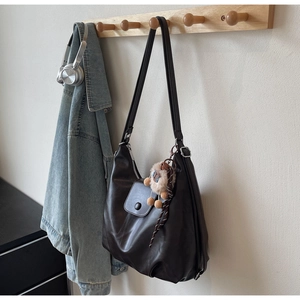 Dettaglio della grande borsa tote in pelle caffè scuro con cerniera e ciondolo peluche