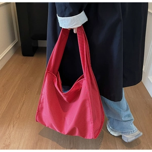 Gros plan du grand sac cabas en tissu à carreaux rouge et blanc porté par un mannequin