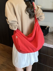 Minimalist red crescent crossbody bag with adjustable wide strap and nylon texture