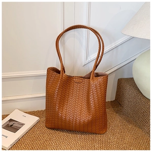 Close-up of brown woven tote bag featuring high-quality leather texture and cross-weave craft