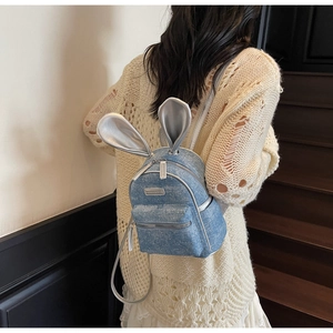 Detail view of denim mini backpack with sequin finish and silver rabbit ears on straps