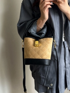 Sac seau matelassé beige et noir avec fermoir doré et texture en daim de luxe