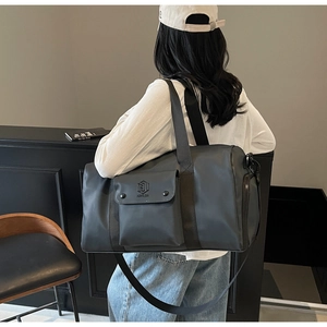 Detailed view of dark grey waterproof gym bag with adjustable strap worn by a model
