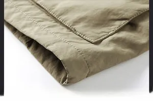 Detail of cargo jacket hem featuring durable double stitching and olive fabric texture