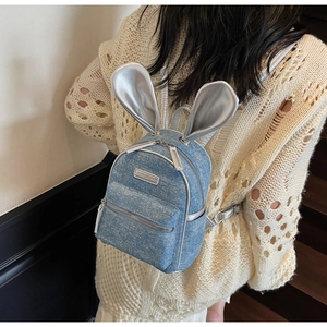 Detail of blue sequin denim mini backpack featuring silver bunny ears and zipper pocket