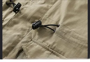 Detail of adjustable waist drawstring with black plastic toggles on a khaki outdoor jacket