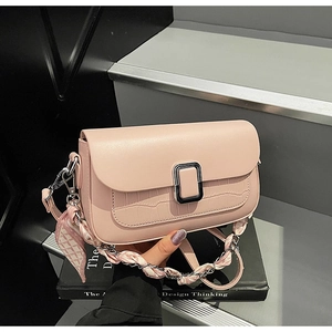 Detail of light pink shoulder bag with crocodile embossing and silk scarf chain strap