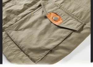 Detail of khaki cargo jacket featuring a contrast orange pocket lining and metal snap button