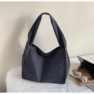 Détail d'un grand sac cabas à carreaux bleu marine à côté d'un ordinateur pour le travail