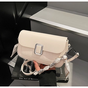 Detail of beige crossbody bag featuring crocodile pattern flap and silver buckle closure