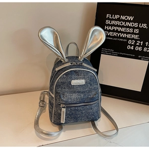Detail of blue denim mini backpack with silver rabbit ears and metallic brand plate