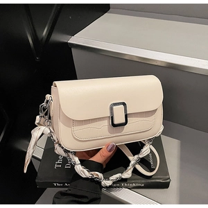 Close-up of cream flap shoulder bag featuring crocodile texture and silk scarf chain strap