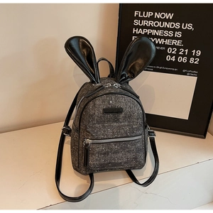 Close-up of gray tweed mini backpack featuring black leather bunny ears and silver zippers