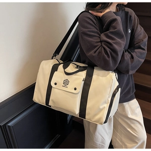 Off-white large gym bag with black straps worn as a crossbody bag for fitness travel