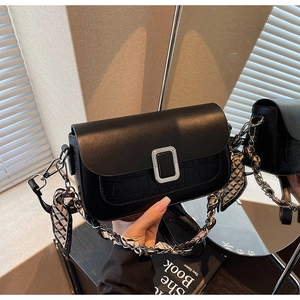 Detail of black crossbody bag with faux crocodile texture and silk scarf chain strap