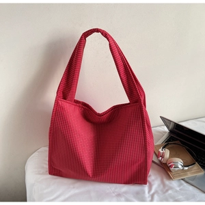 Gros plan du sac cabas à carreaux rouges avec ordinateur et casque sur fond blanc