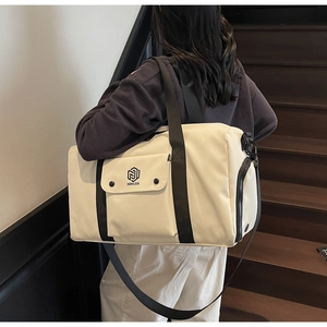 Detail of a beige fitness bag featuring a wet/dry side pocket and black shoulder strap