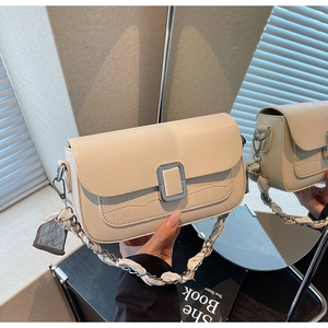 Detail of off-white crossbody bag featuring crocodile texture and silk scarf chain strap