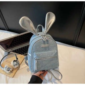 Close-up of mini blue denim backpack with shiny silver bunny ears and sequin details