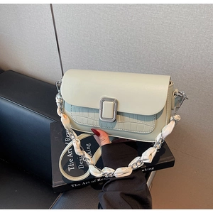 Detail of pistachio green crocodile embossed crossbody bag with silver chain and silk scarf