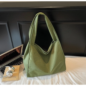 Gros plan d'un grand sac cabas à carreaux verts avec larges bandoulières en décor de bureau