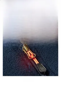 Detailed close-up of a durable metal zipper with orange pull cord on a warm fleece jacket