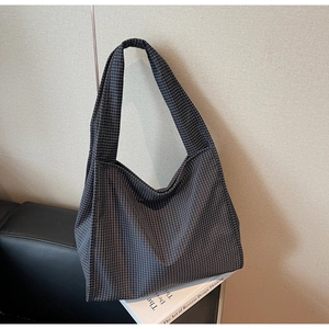Détail d'un grand sac cabas en toile avec motif à carreaux foncés et bandoulière