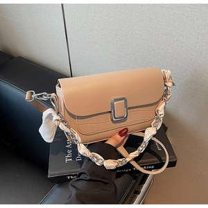 Detail of beige crossbody bag with crocodile texture and silk scarf chain strap