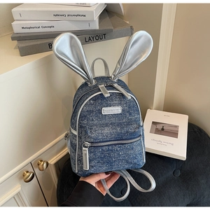 Close-up of cute blue denim mini backpack with silver rabbit ears and fashion label