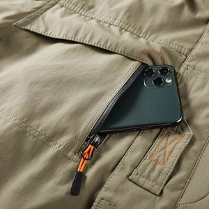 Mens khaki outdoor cargo jacket pocket detail with orange zipper pull and phone storage