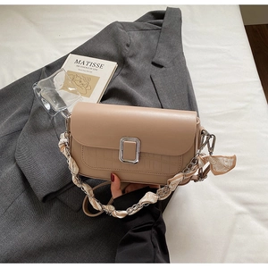 Detail of beige shoulder bag with crocodile texture, silver clasp and scarf chain strap