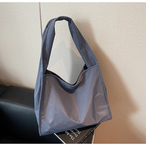 Détail du sac cabas à carreaux bleus montrant la texture toile près d'un livre