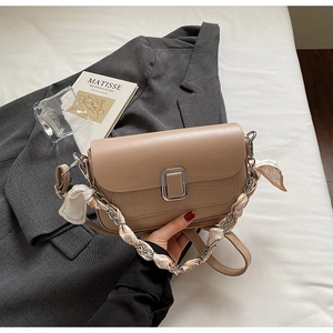 Detail of khaki flap bag featuring faux crocodile texture and silk scarf handle detail