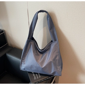 Gros plan du sac cabas à carreaux bleus et de sa large bandoulière sur une chaise