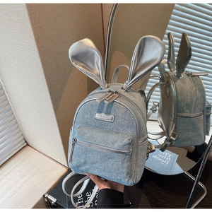 Detail of light blue denim mini backpack featuring silver rabbit ears and metallic accents