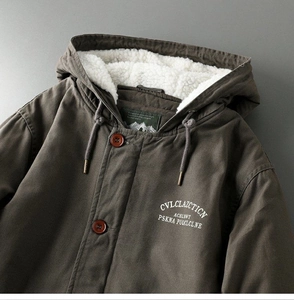 Close-up of olive green parka with warm white sherpa lining and embroidery details