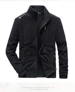 Detail of black fleece jacket with standing collar and hidden zipper pockets on chest