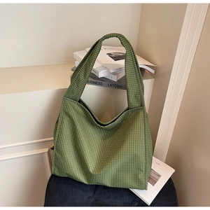 Détail du sac cabas à carreaux verts de style hobo posé sur une chaise en velours