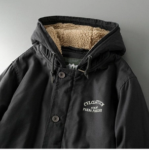 Close-up of black hooded jacket featuring warm beige sherpa lining and letter print