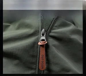 Detail of dark metal zipper with a brown leather puller and OUTDOOR logo on jacket