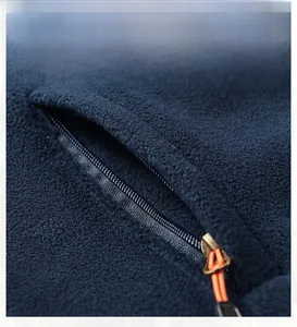 Detail of dark blue fleece jacket showing a zip pocket with orange pull cord accent