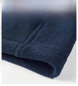 Macro shot of dark blue fleece jacket hem with precise flat-seam stitching and thick fabric